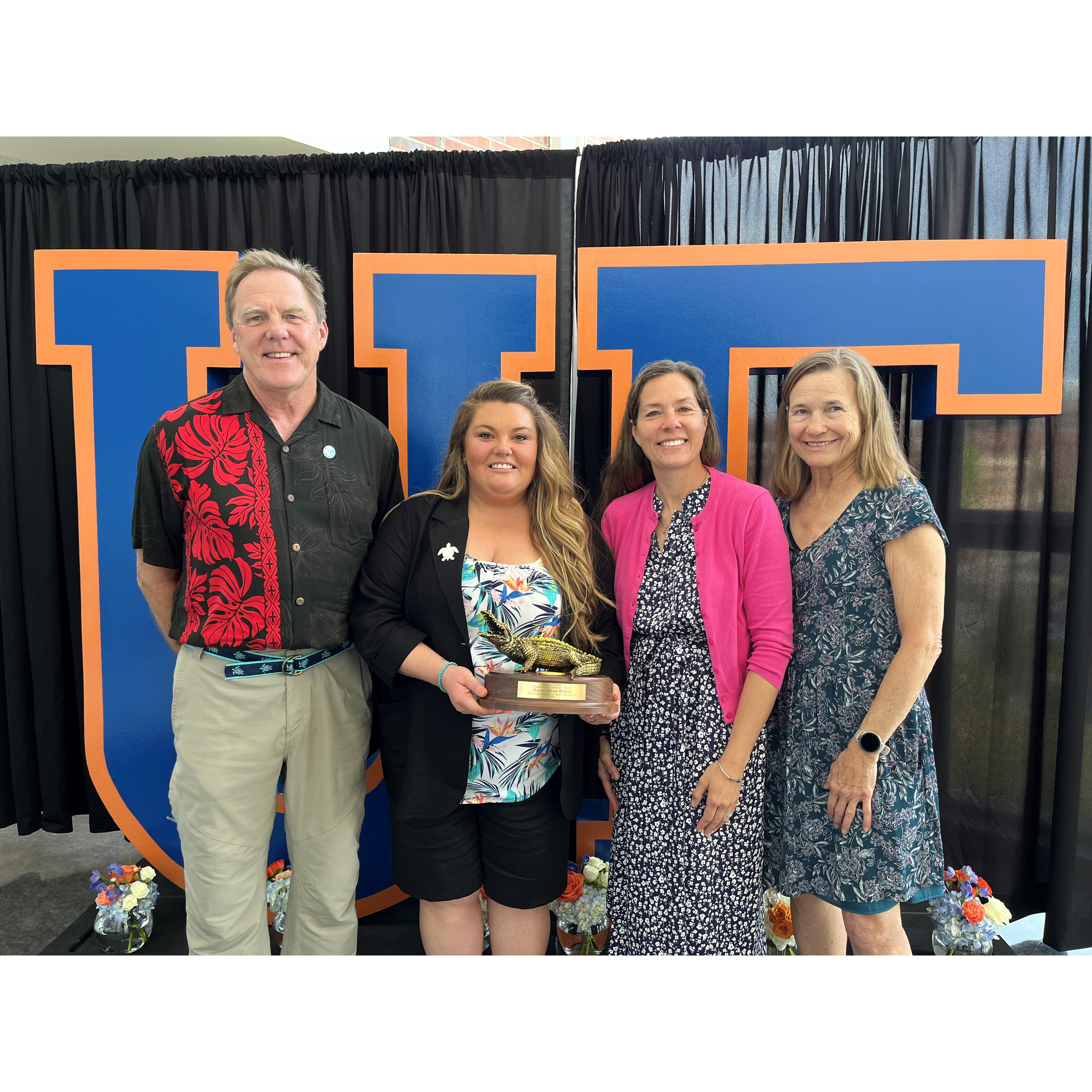 Group of people behind UF letters with one holding an award