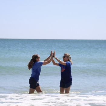 Women high fiving in ocean